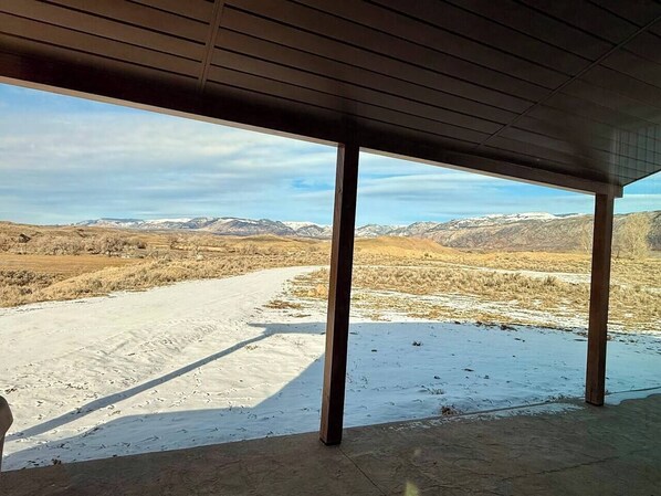Un espace extérieur abrité offrant une vue sur un paysage enneigé et des montagnes au loin.