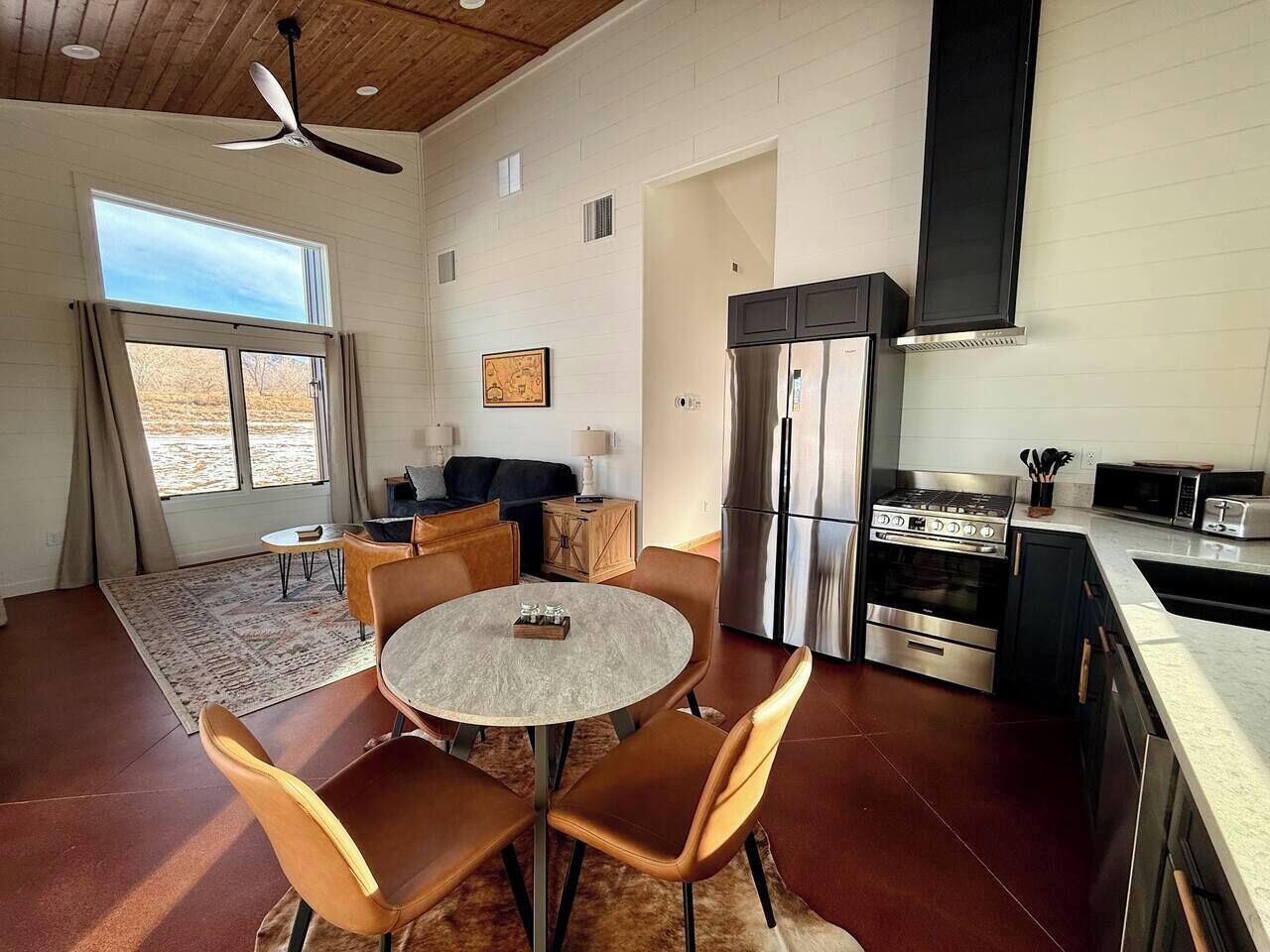 A modern kitchen with a central island, stainless steel appliances, and a dining area with a round table and chairs.