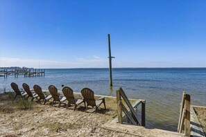 A beach with wooden chairs and a wooden pier extending into the water. - Beach Rabbit | 1200 ft to the beach | Private Pool and Hot Tub (Southern Shores)