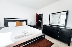 A hotel room with a large bed, a bedside table, a dresser, and a mirror.