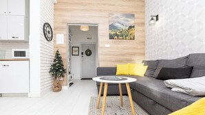 Una sala moderna con un sofá gris, una mesita redonda y un árbol de Navidad.