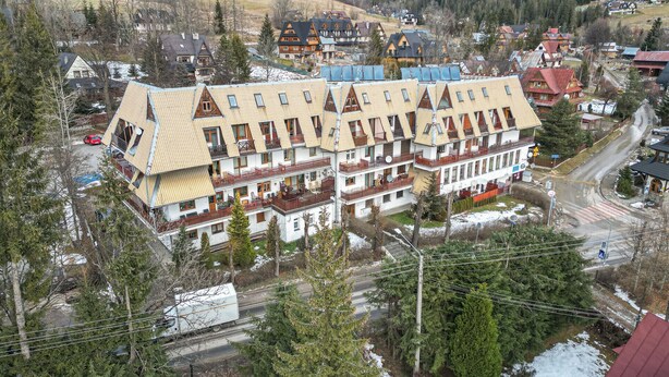 Un edificio de varios pisos con techo inclinado, balcones y una combinación de espacios residenciales y comerciales.