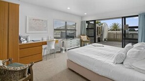 A bedroom with a bed, a desk, and a chair. There is a window with a view of the outside.