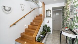 A wooden staircase with a handrail, a door with a sign, and a wall with a floral pattern.