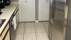 A compact kitchen with a stainless steel refrigerator, a coffee maker, and a tiled backsplash.