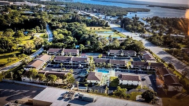 An aerial view of a residential area with multiple buildings, a swimming pool, and a road.