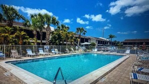 A rectangular pool with clear blue water, surrounded by a tiled deck and white lounge chairs.