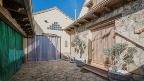 Une cour avec un sol en pierre, une porte en bois et des plantes en pot.