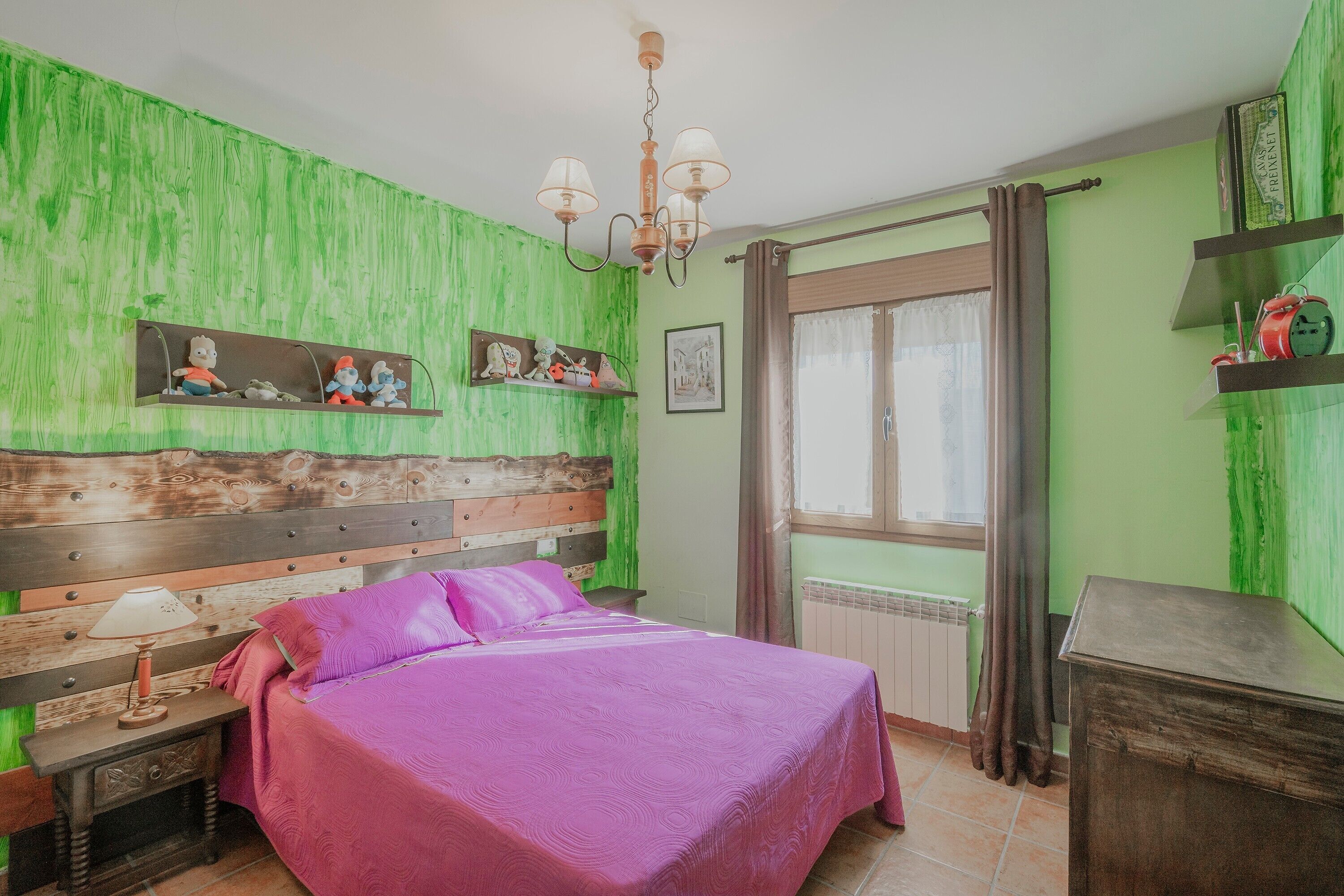 Quarto com cama, mesa de cabeceira, cabeceira de madeira, janela com cortinas e parede verde.