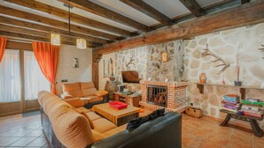 Un salon chaleureux avec une cheminée, un canapé, un téléviseur et un mur en pierre.
