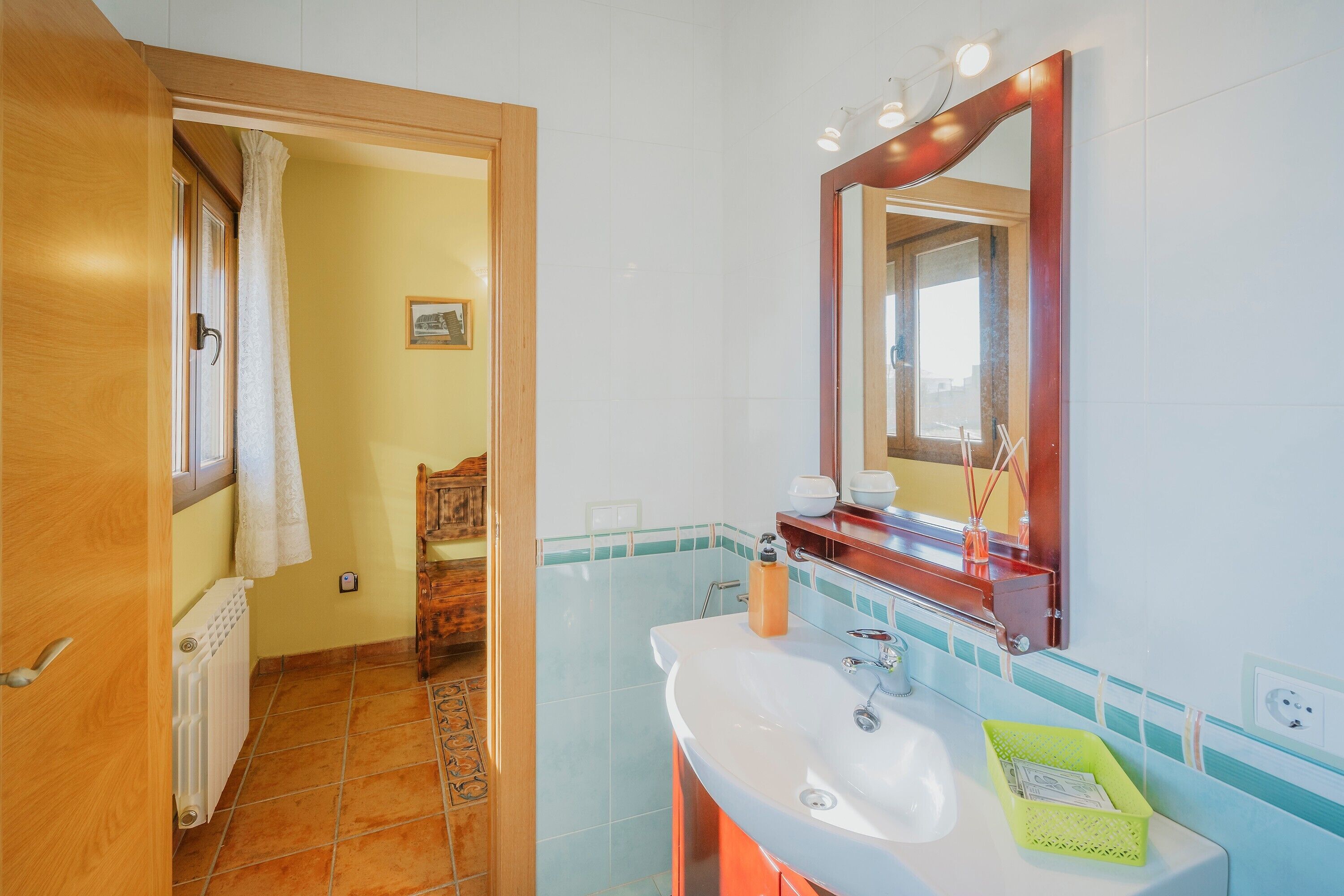 Un baño con lavamanos, espejo y perchero para toallas.