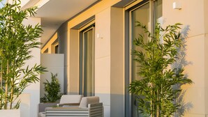 A modern outdoor seating area with a sofa and table, surrounded by potted plants and a large window. - Villa '11 Sunset' with Mountain View, Wi-Fi and Air Conditioning (Marbella)