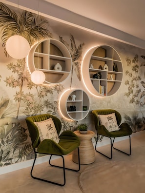 Un interior moderno con estantes circulares, sillones tapizados en verde y un mural en la pared.