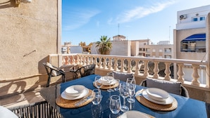 Une terrasse sur le toit avec une table dressée pour le dîner, une vue sur la ville et un appareil de climatisation LG.