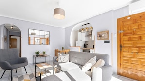Un salon moderne avec un canapé gris, une table basse et un fauteuil gris.