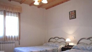 A bedroom with two single beds, a radiator, a window with curtains, and a wooden ceiling. - Country House 'El Fronton' with Mountain View (Vadillo)
