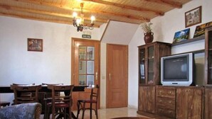 A dining area with wooden furniture, a television on a cabinet, and a chandelier. - Country House 'El Fronton' with Mountain View (Vadillo)