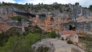 A rocky landscape with a cave entrance, a small building with a red roof, and a metal walkway. - Country House 'El Fronton' with Mountain View (Vadillo)