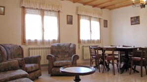 A room with a sofa set, a dining table with chairs, and a radiator. - Country House 'El Fronton' with Mountain View (Vadillo)