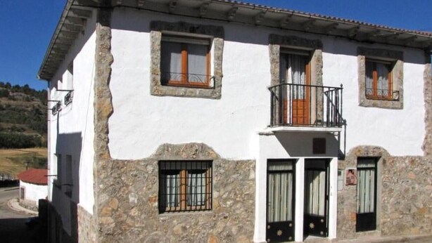 A two-story building with stone walls, a balcony, and a small porch. - Country House 'El Fronton' with Mountain View (Vadillo)