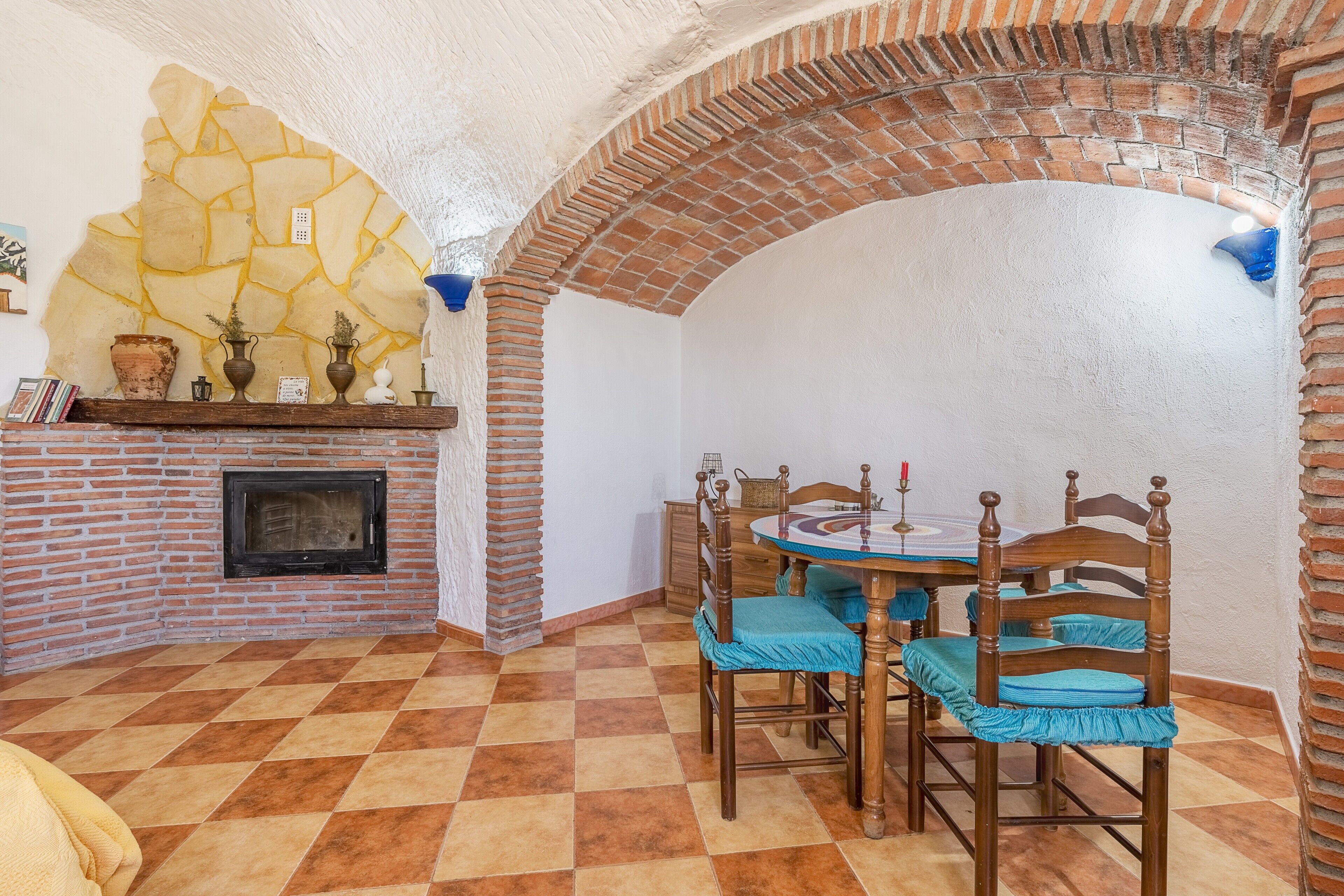 Un coin repas avec une cheminée en briques, un sol à carreaux et une table entourée de chaises.