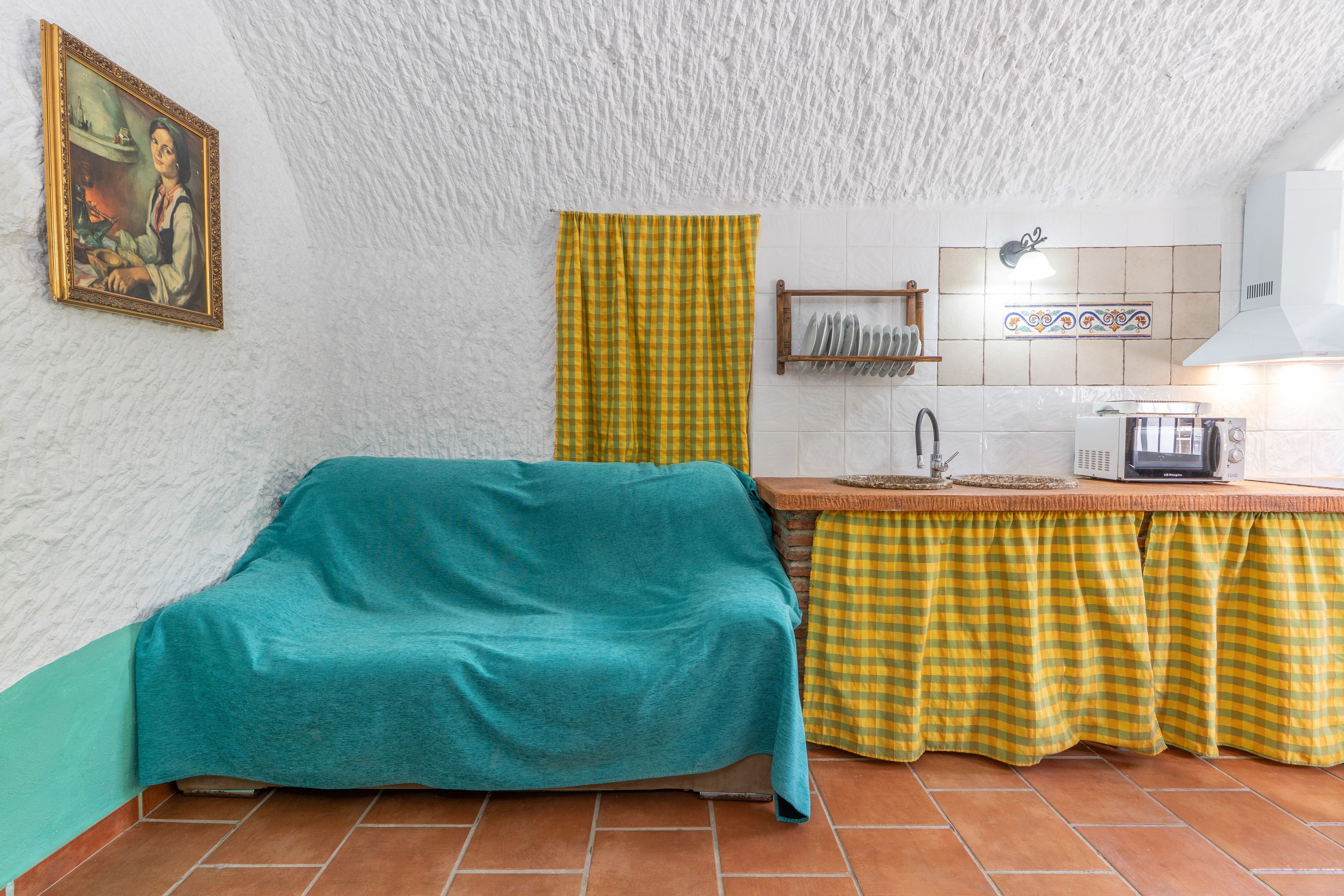 Una cocina compacta con salpicadero de azulejos, microondas, tostadora y un lavamanos.