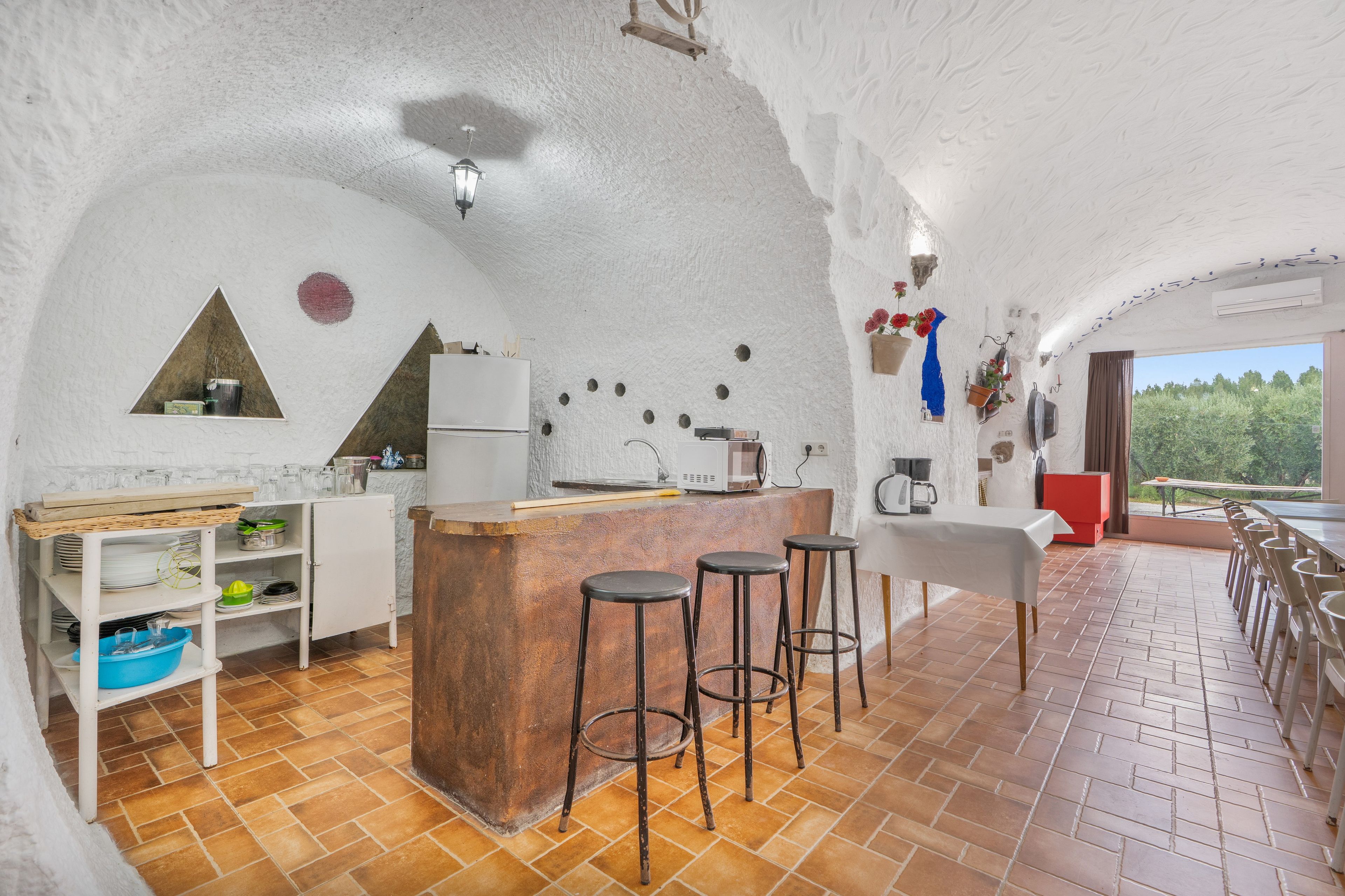 A kitchen with a central island, bar stools, and a dining area with a table and chairs.
