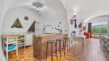 A kitchen with a central island, bar stools, and a dining area with a table and chairs.