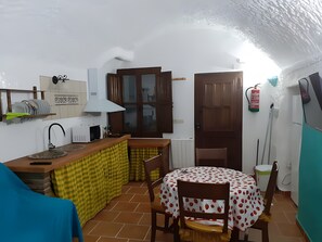 Eine kompakte Küche mit Spüle, Mikrowelle und einem Essbereich mit Tisch und Stühlen.