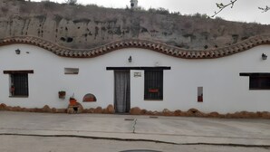Un edificio con fachada blanca, techo de tejas y patio empedrado.