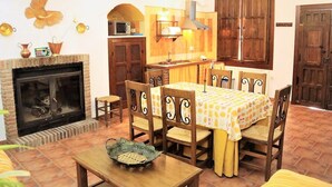 A cozy living room with a fireplace, wooden furniture, and a dining area. - Country House 'Los Jazmines' with Shared Pool, Wi-Fi and Air Conditioning (Benalúa)