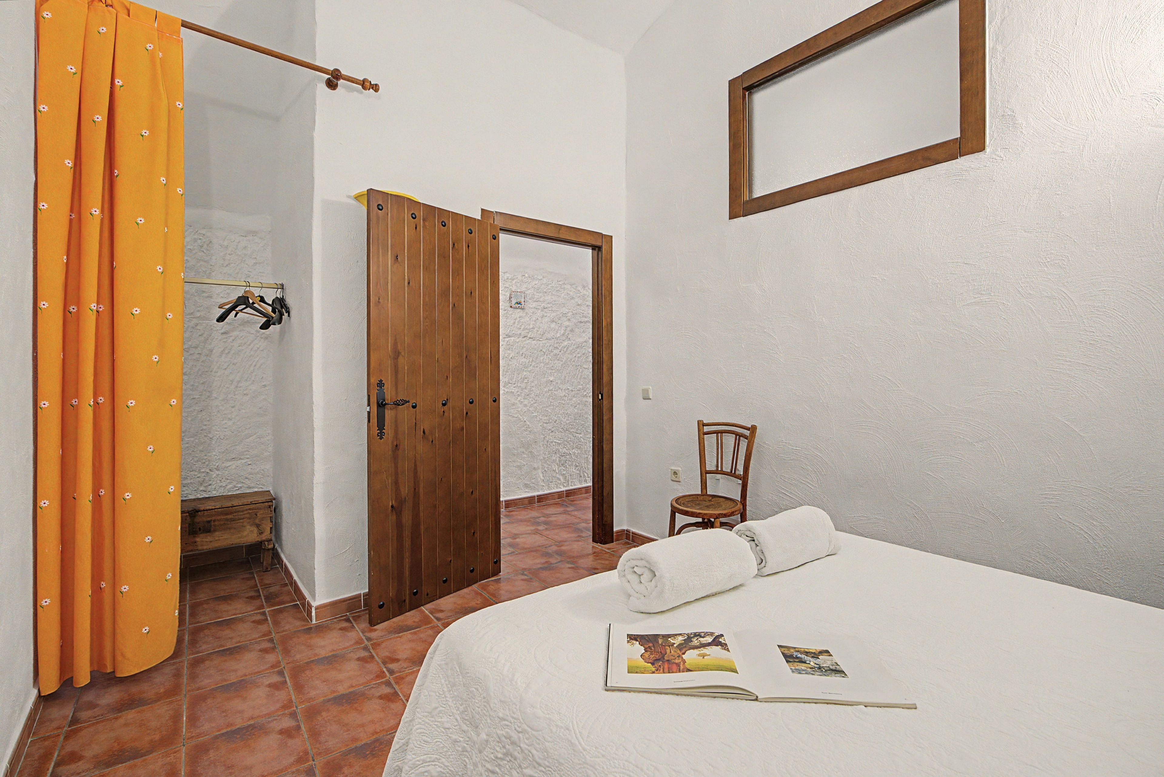 A bedroom with a bed, a wooden door, a chair, and a window.
