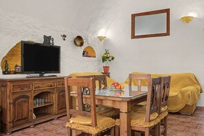A cozy living room with a television, wooden furniture, and decorative wall elements. - Country House 'Los Jazmines' with Shared Pool, Wi-Fi and Air Conditioning (Benalúa)