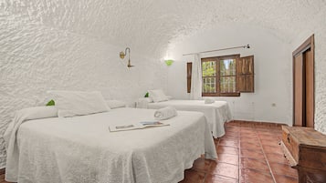 Een kamer met twee bedden, een houten bank en een raam met gordijnen.
