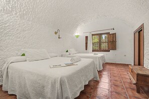 Una habitación con dos camas, un banco de madera y una ventana con cortinas.
