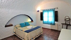 A bedroom with a bed, a window with curtains, a chair, and a small table. - Country House 'Los Jazmines' with Shared Pool, Wi-Fi and Air Conditioning (Benalúa)
