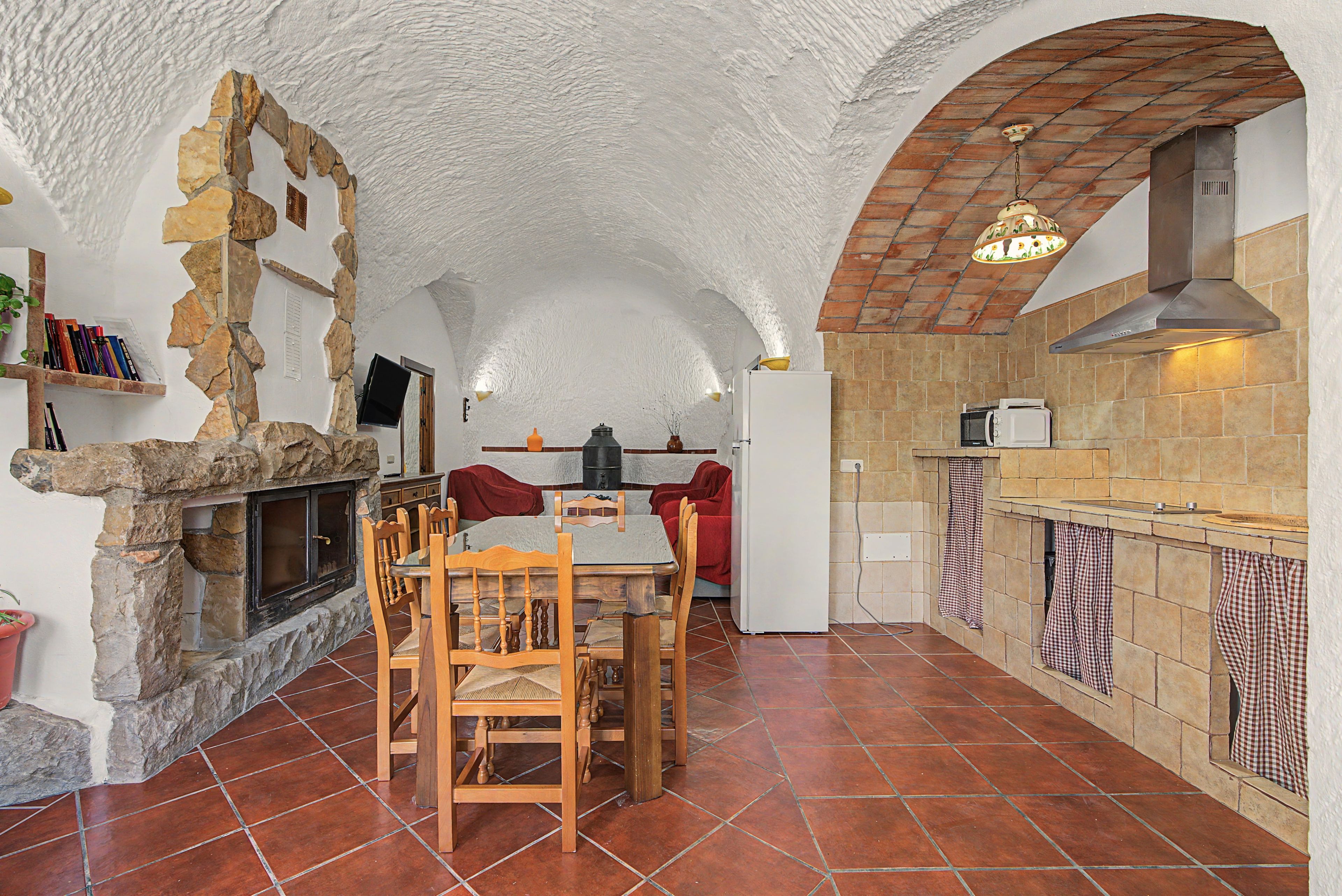 Une cuisine rustique avec des murs en pierre, un sol carrelé et un coin repas doté de meubles en bois.