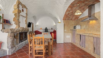 Une cuisine rustique avec des murs en pierre, un sol carrelé et un coin repas doté de meubles en bois.