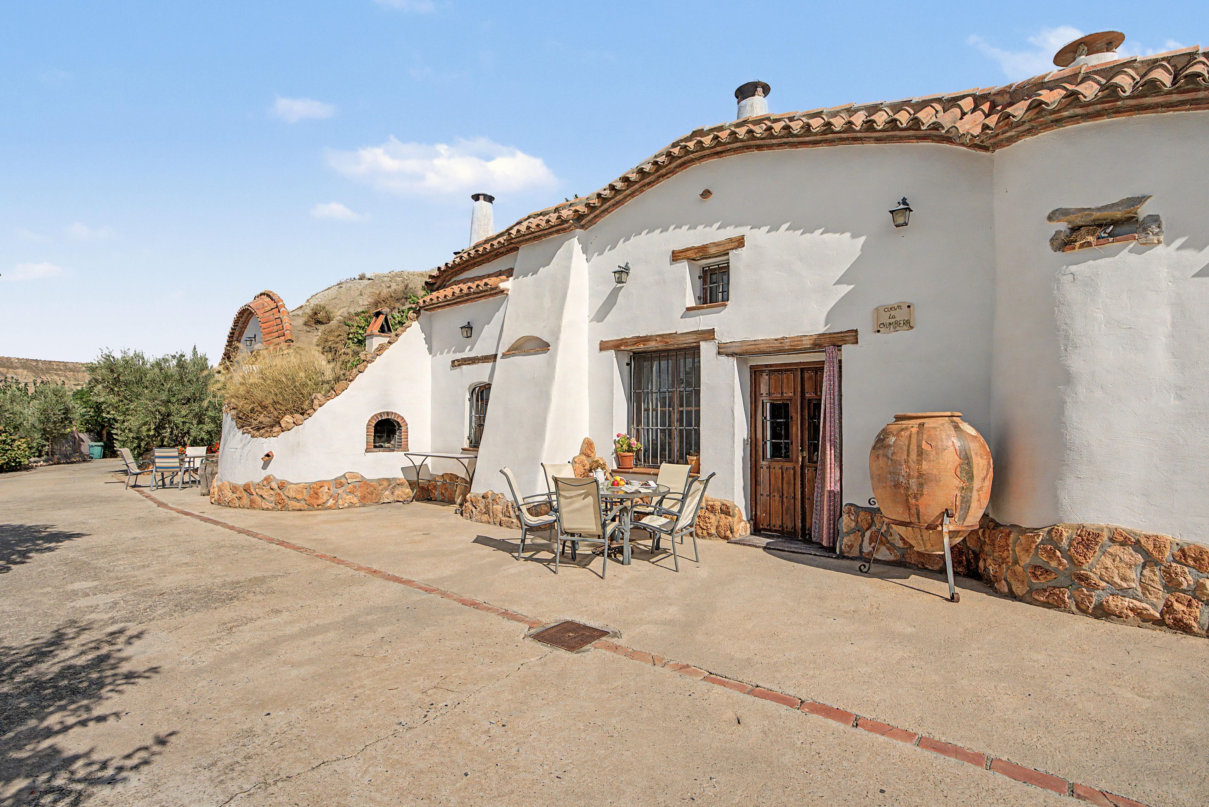 Un bâtiment traditionnel doté d’un patio, d’un espace extérieur aménagé et d’un grand pot de fleurs.