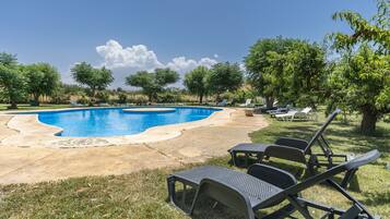 A swimming pool with lounge chairs and trees in the background.