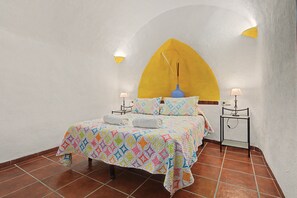 Une chambre à coucher comprenant un lit, deux tables de chevet, une commode, une lampe et un luminaire fixé au mur.