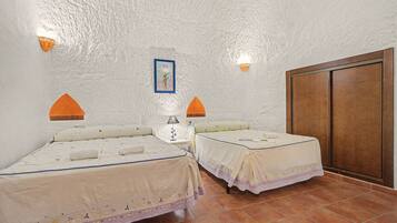 A hotel room with two beds, a nightstand, a lamp, a picture on the wall, and a wardrobe.