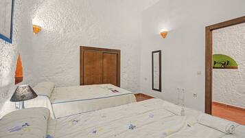 Un dormitorio con dos camas, un armario de madera, un espejo y una pared con textura.