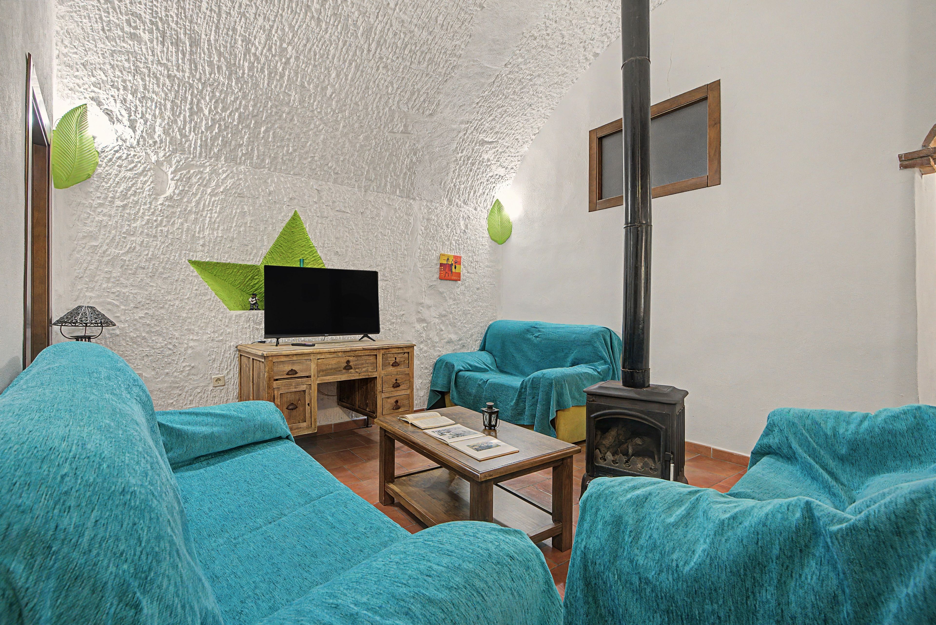 Una sala de estar con televisor, mueble de madera, sofá y chimenea.