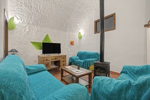 A living room with a television, wooden cabinet, sofa, and a fireplace. - Country House 'El Granado' with Shared Pool, Wi-Fi and Air Conditioning (Benalúa)