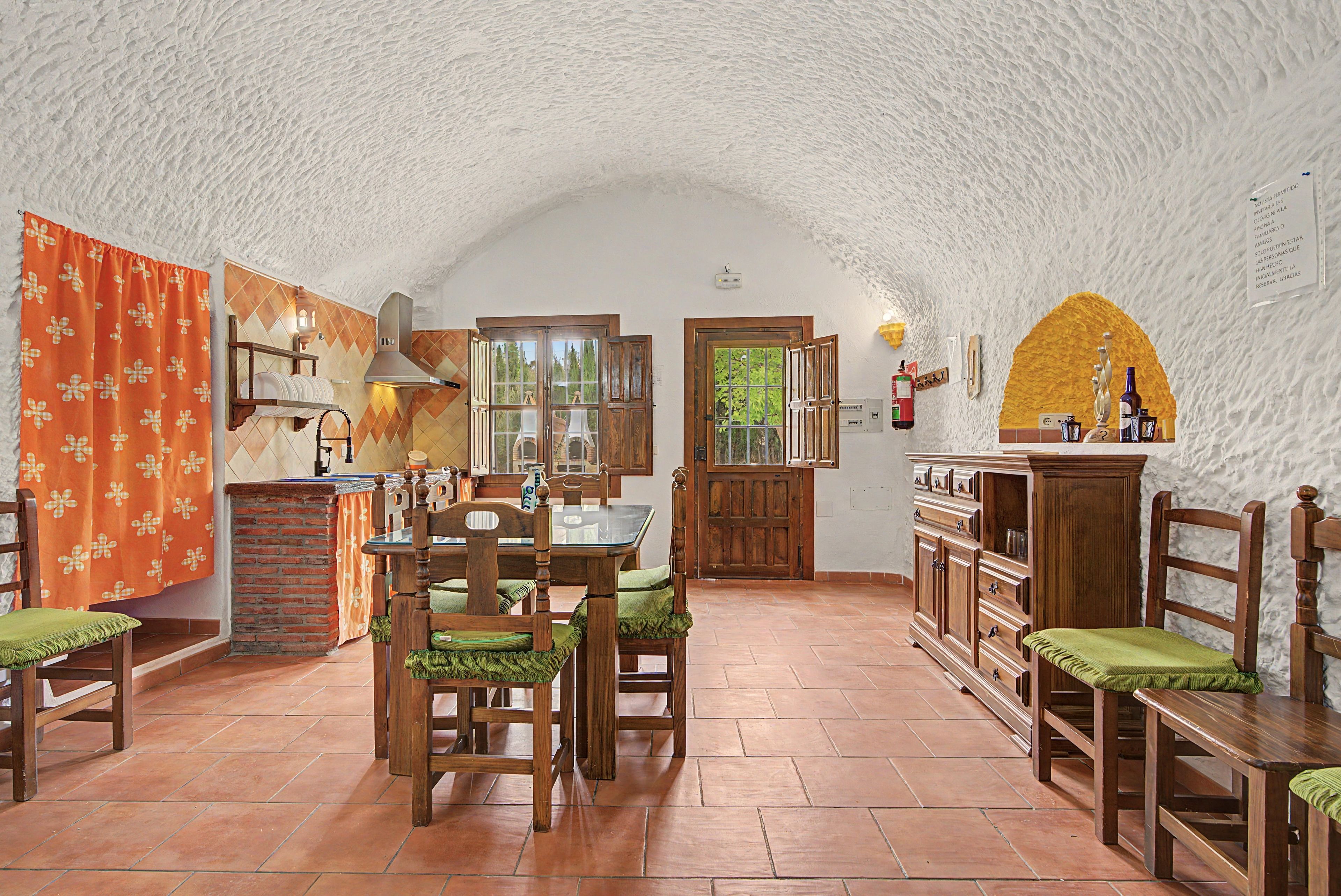 A dining area with wooden furniture, a brick fireplace, and a view through the open door.