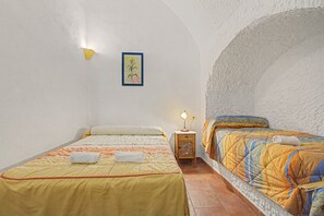 A bedroom with two beds, a nightstand, a wall-mounted lamp, and a framed botanical illustration. - Country House 'El Granado' with Shared Pool, Wi-Fi and Air Conditioning (Benalúa)