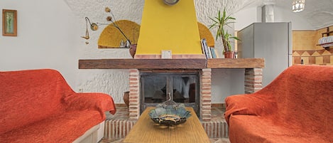 A cozy living room with a fireplace, two red sofas, and a wooden coffee table.