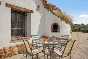 An outdoor patio with a table, chairs, and a small garden area. - Country House 'El Olivo' with Shared Pool, Wi-Fi and Air Conditioning (Benalúa)