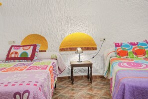 A room with two beds, a small table, a lamp, and a wall with a textured finish. - Country House 'El Olivo' with Shared Pool, Wi-Fi and Air Conditioning (Benalúa)